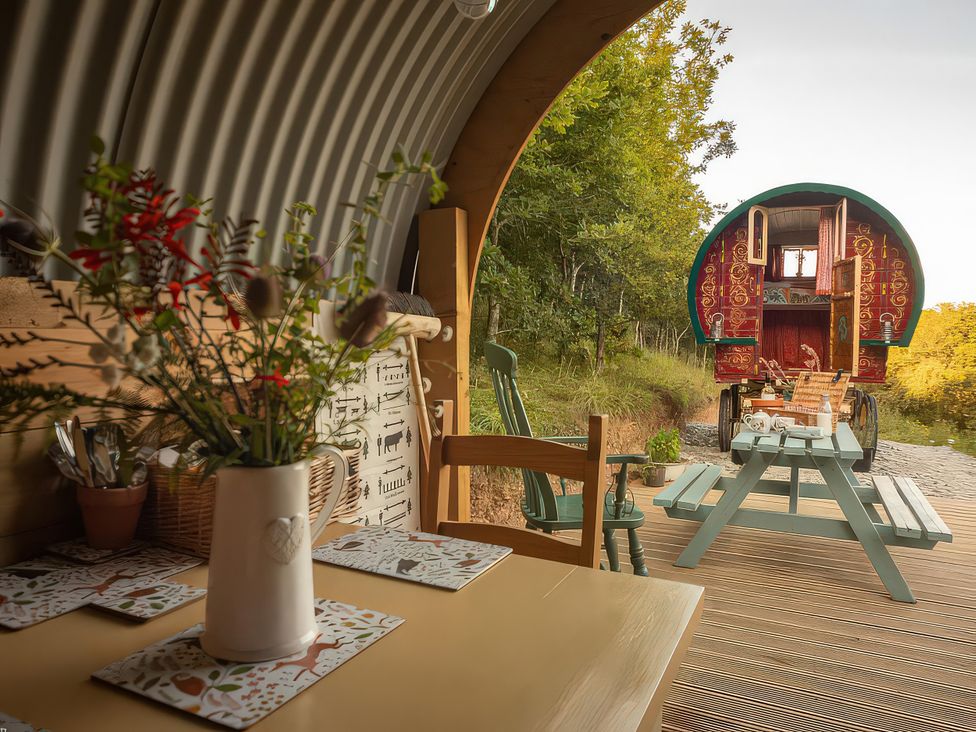 A dining area with a flower vase and a view of a caravan at Goldfinch in Launceston