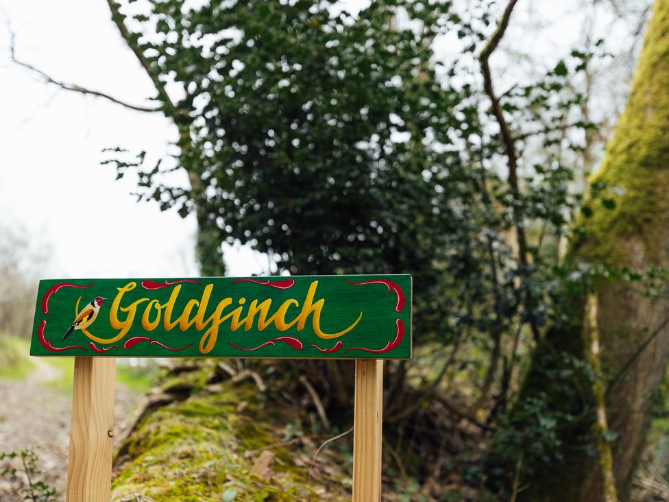 A wooden sign that reads Goldfinch in a wooded area at Goldfinch in Launceston