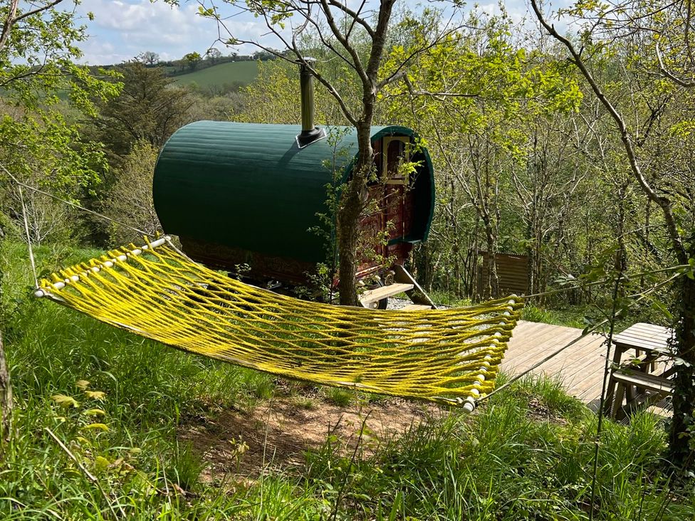 A hammock near a green cabin in the woods at Goldfinch Panson Mill near Ashwater