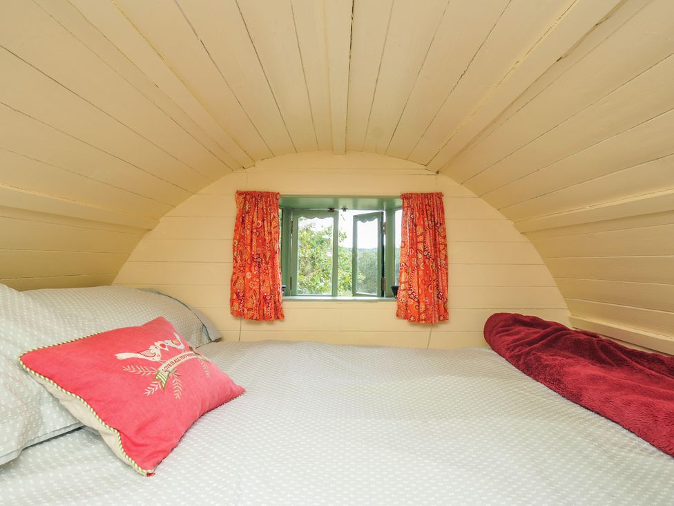 A bedroom with a bed and window at Goldfinch in Panson Mill near Ashwater