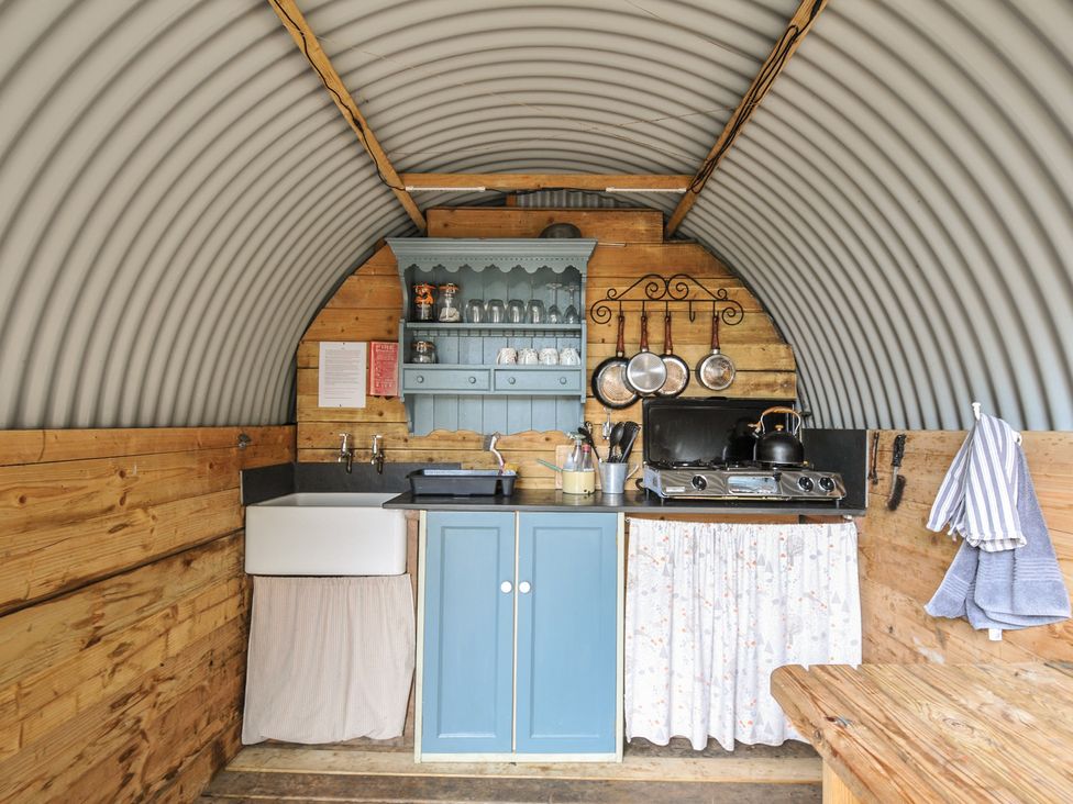 A kitchen with wooden cabinets and a stove at Goldfinch in Panson Mill near Ashwater