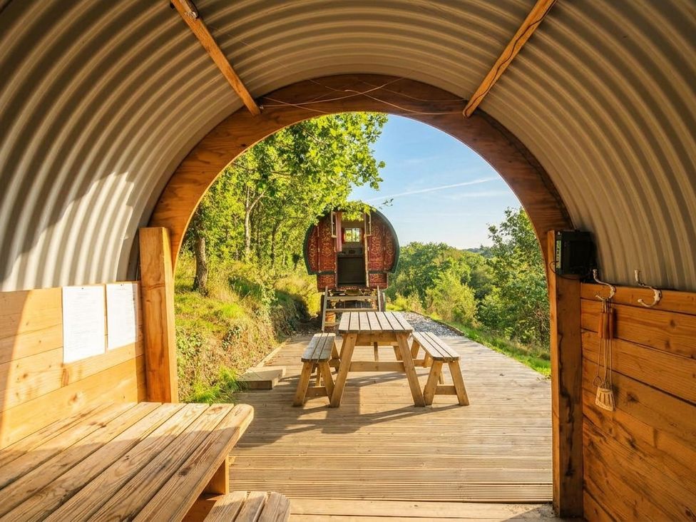 An outdoor seating area with wooden table and benches at Goldfinch in Panson Mill near Ashwater