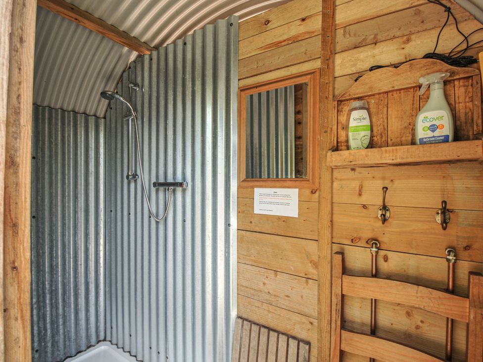A shower with striped metal wall and wooden elements at Prudence in Panson Mill near Ashwater