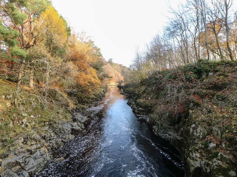 A river flowing between rocky banks with trees on either side at 17C King Street Barnard Castle