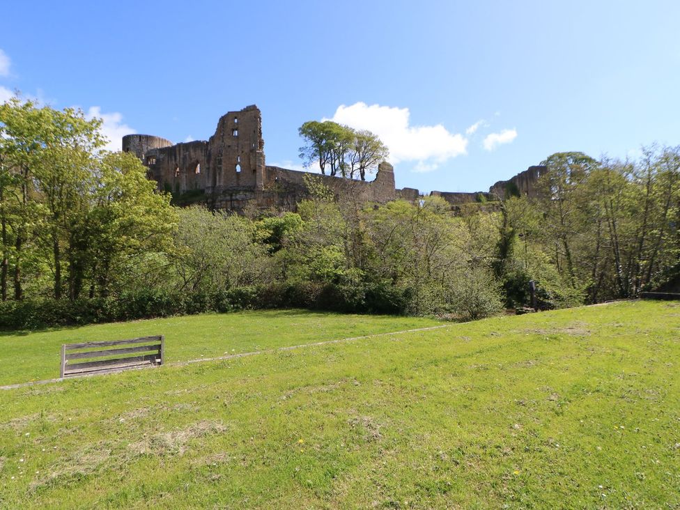 A view of ruins with trees and a bench in a field at 17C King Street in Barnard Castle