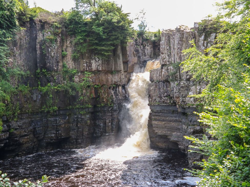 A waterfall flowing over rocks surrounded by trees at 17C King Street Barnard Castle
