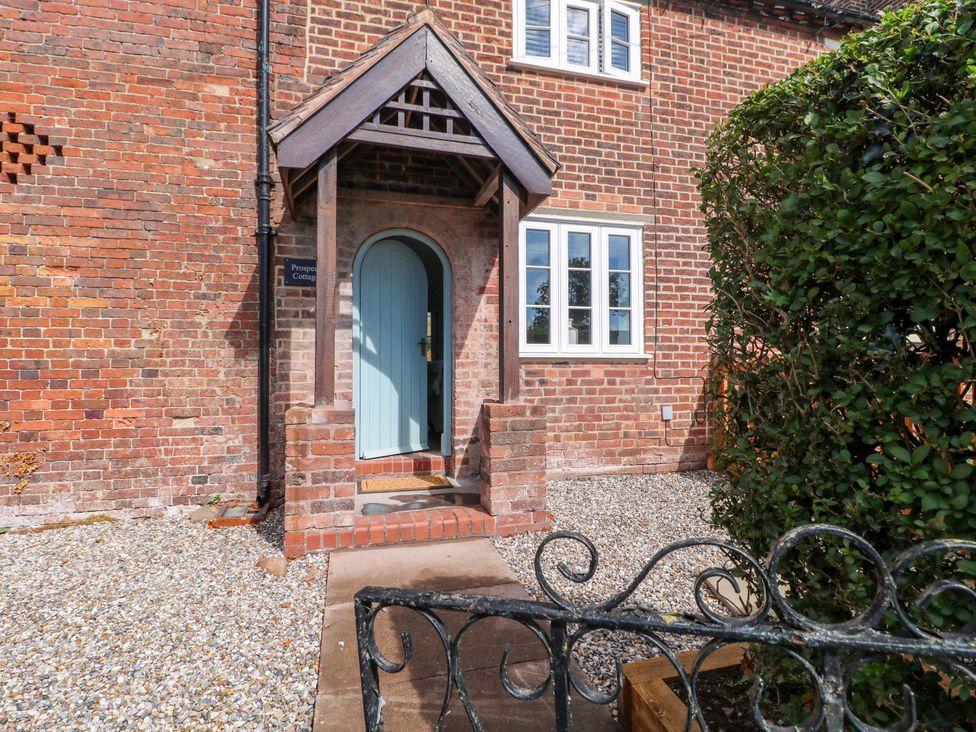 An entrance with a blue door and brick wall at Prospect Cottage