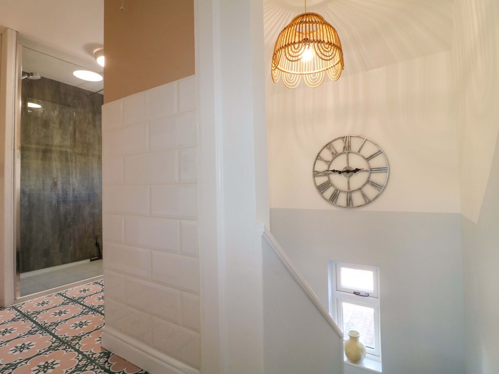 A staircase with a wall clock and light fixture at Prospect Cottage