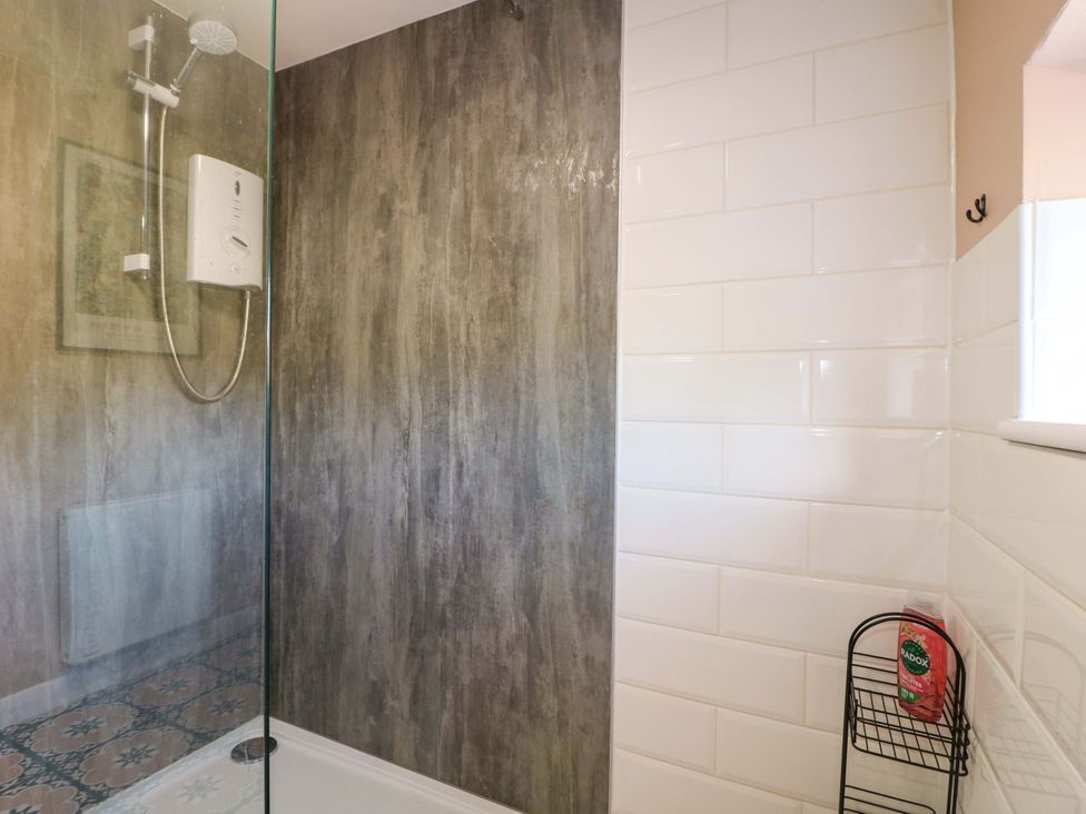 A shower with a glass door and tiled walls at Prospect Cottage