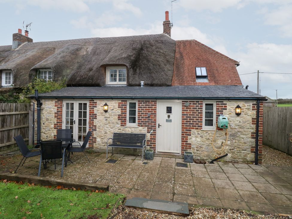 A cottage with a patio and chairs at Bubbs Cottage