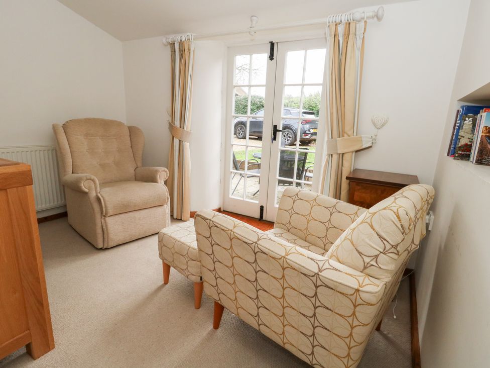 A snug with seating and doors leading to the outside at Bubbs Cottage