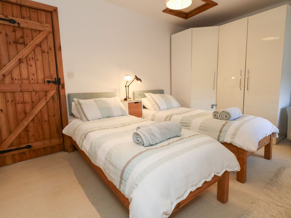 A bedroom with two beds and a wooden door at Bubbs Cottage