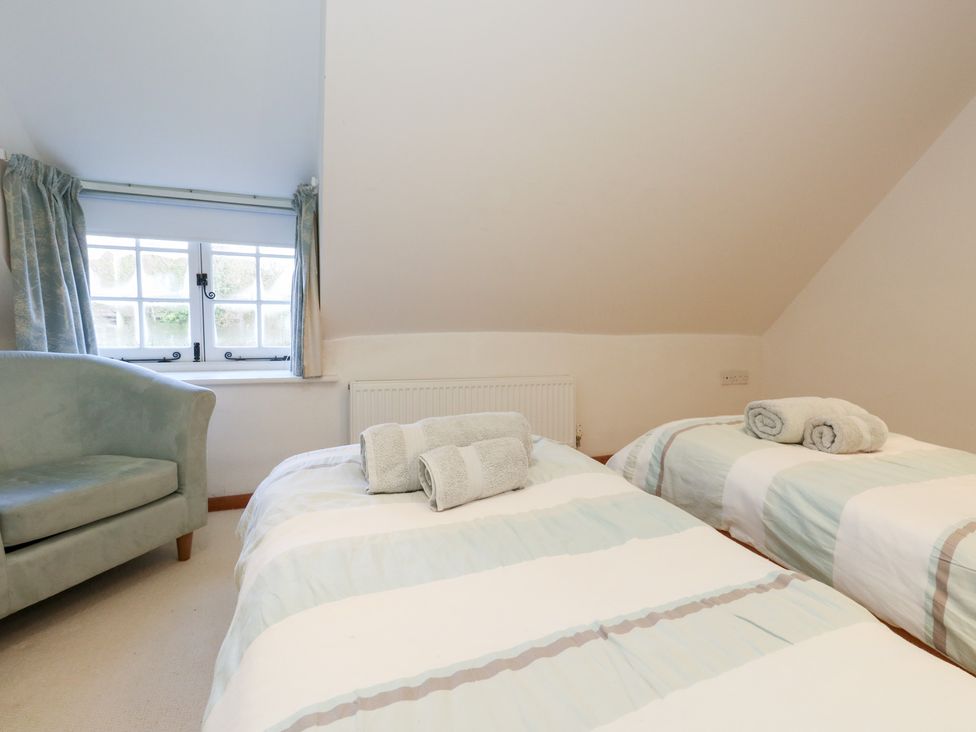 A bedroom with two beds and a chair at Bubbs Cottage