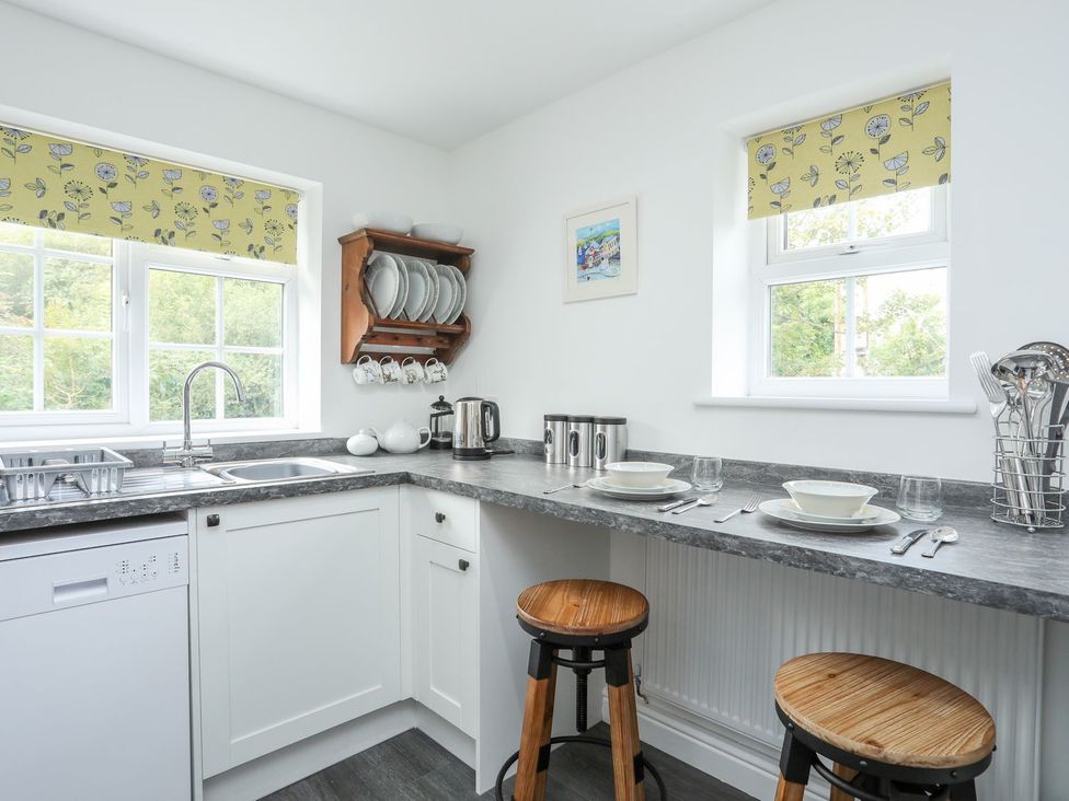 A kitchen with seating and dinnerware at Bryn Bach Pentraeth