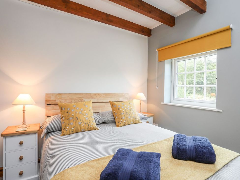 A bedroom with a double bed and bedside lamp at Bryn Bach in Pentraeth
