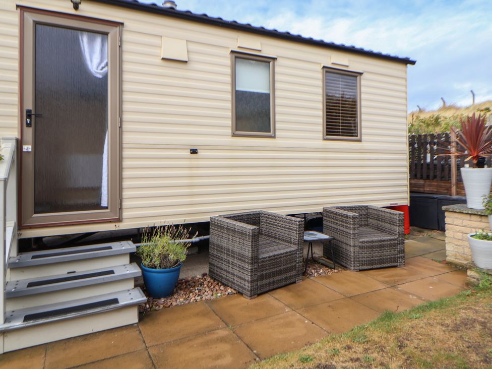 An outdoor area with a caravan, chairs, and a table at Caravan 596, Prestatyn