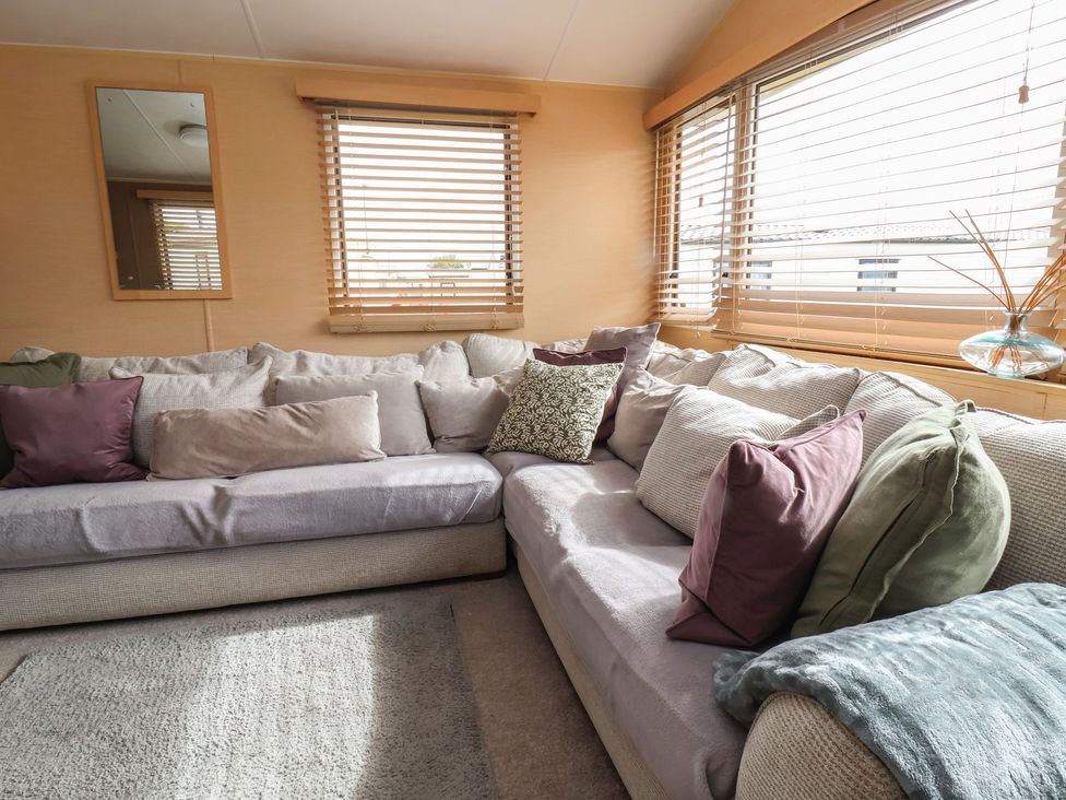 A living room with a sofa and pillows at Caravan 596 in Prestatyn