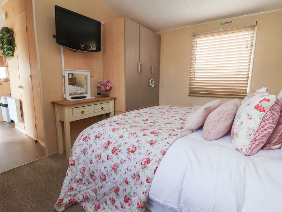 A bedroom with a bed, dresser, and television at Caravan 596 in Prestatyn