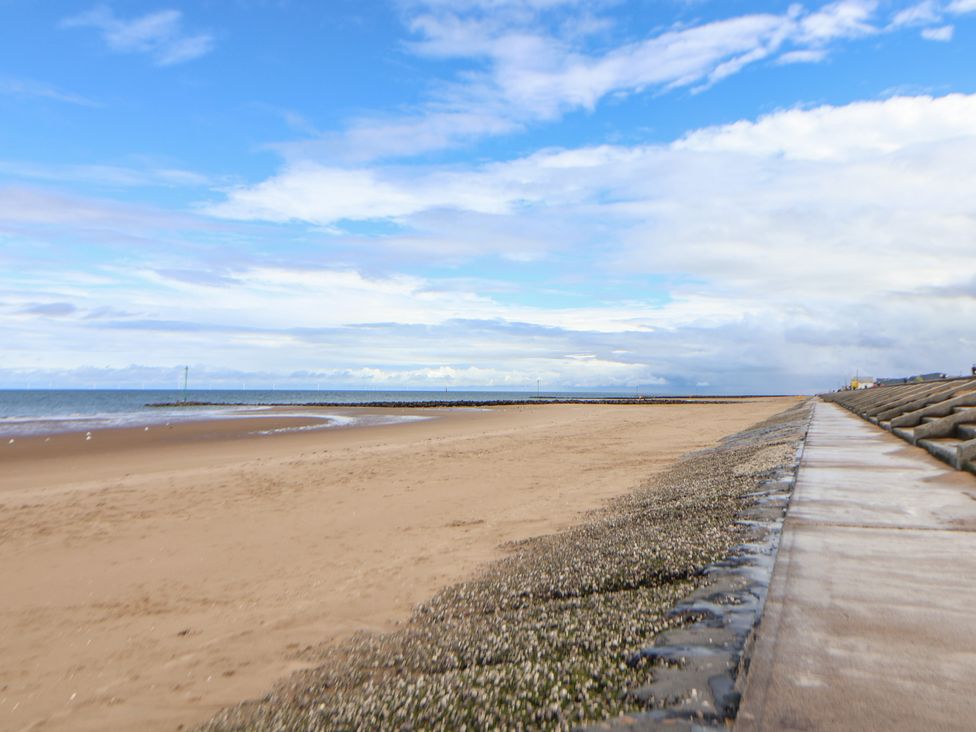A beach with sand and a walkway near the ocean at Caravan 596 Prestatyn