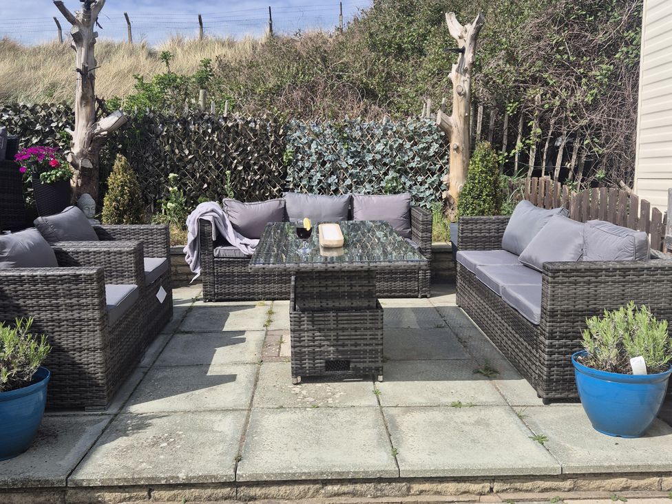 A garden with outdoor seating and a coffee table at Caravan 596 in Prestatyn