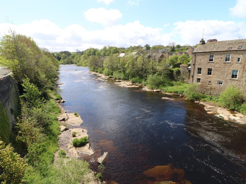 A river bordered by trees and buildings at 1 Kyles Yard Barnard Castle