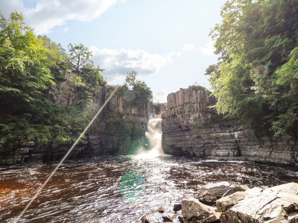 A waterfall in a river surrounded by rock formations and trees at 1 Kyles Yard Barnard Castle