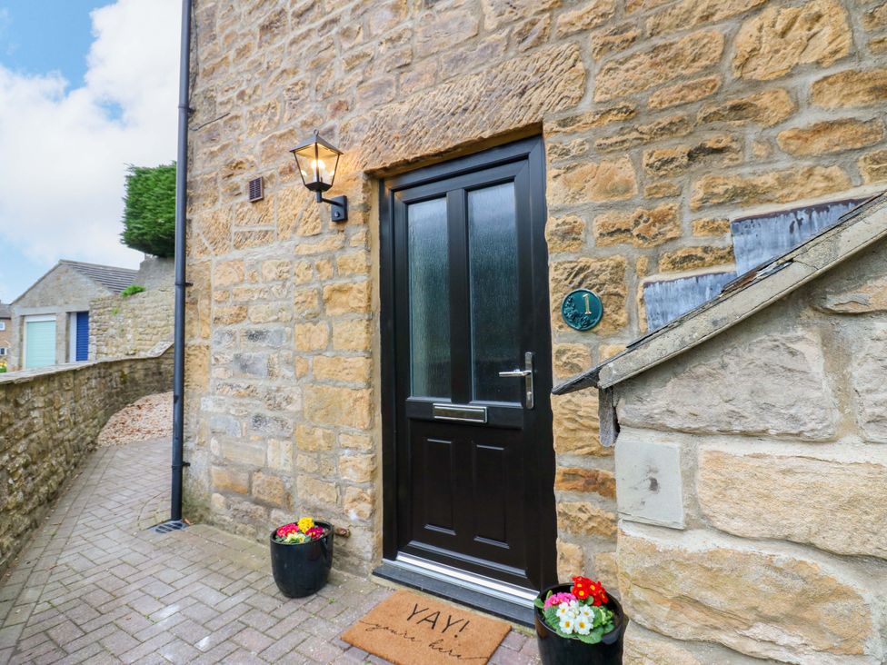 A front door with a mat and flower pots at 1 Kyles Yard Barnard Castle
