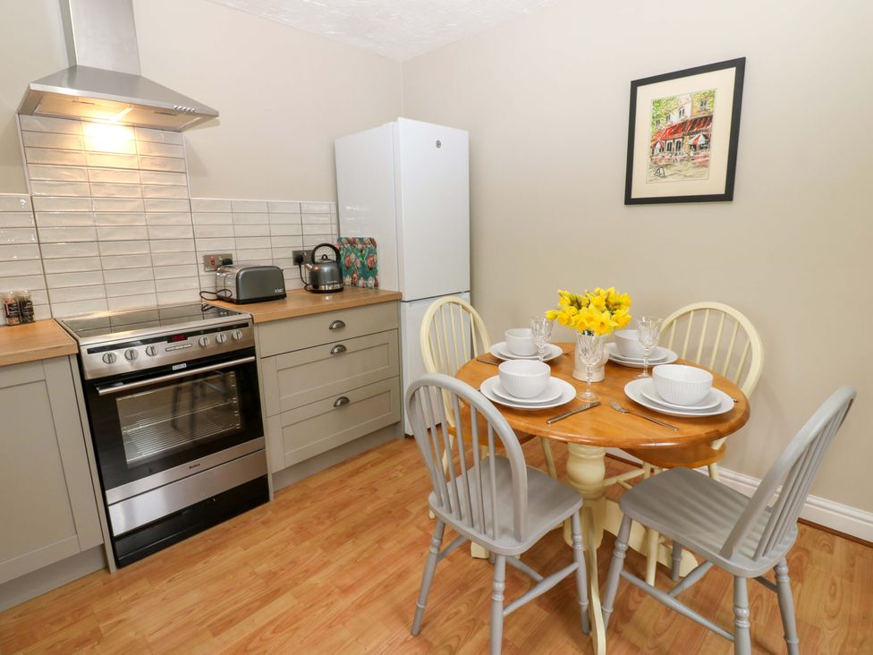 A kitchen with an oven, refrigerator, table, and chairs at 1 Kyles Yard Barnard Castle