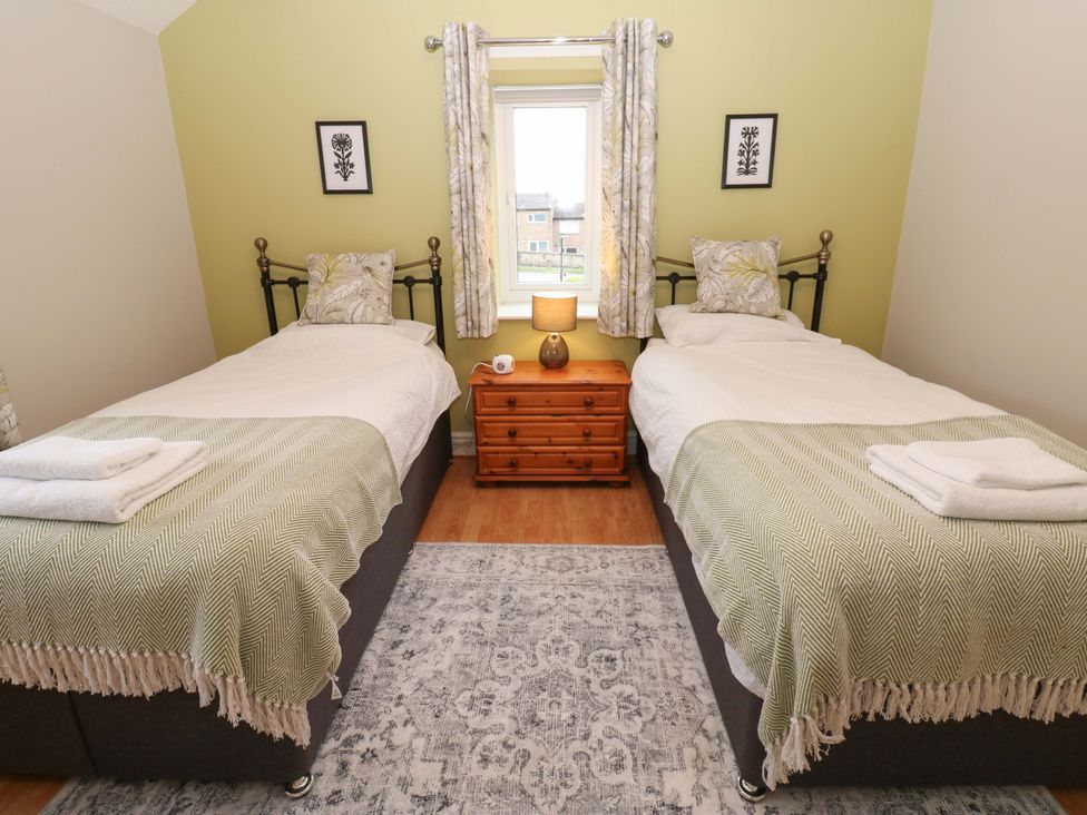 A bedroom with two beds and a wooden table at 1 Kyles Yard Barnard Castle