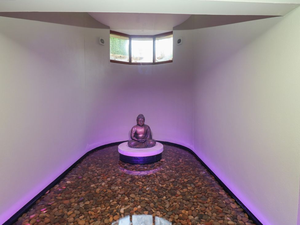 A spa with a Buddha statue on a pedestal surrounded by pebbles at Costal Lodge at Seaham Hall Seaham
