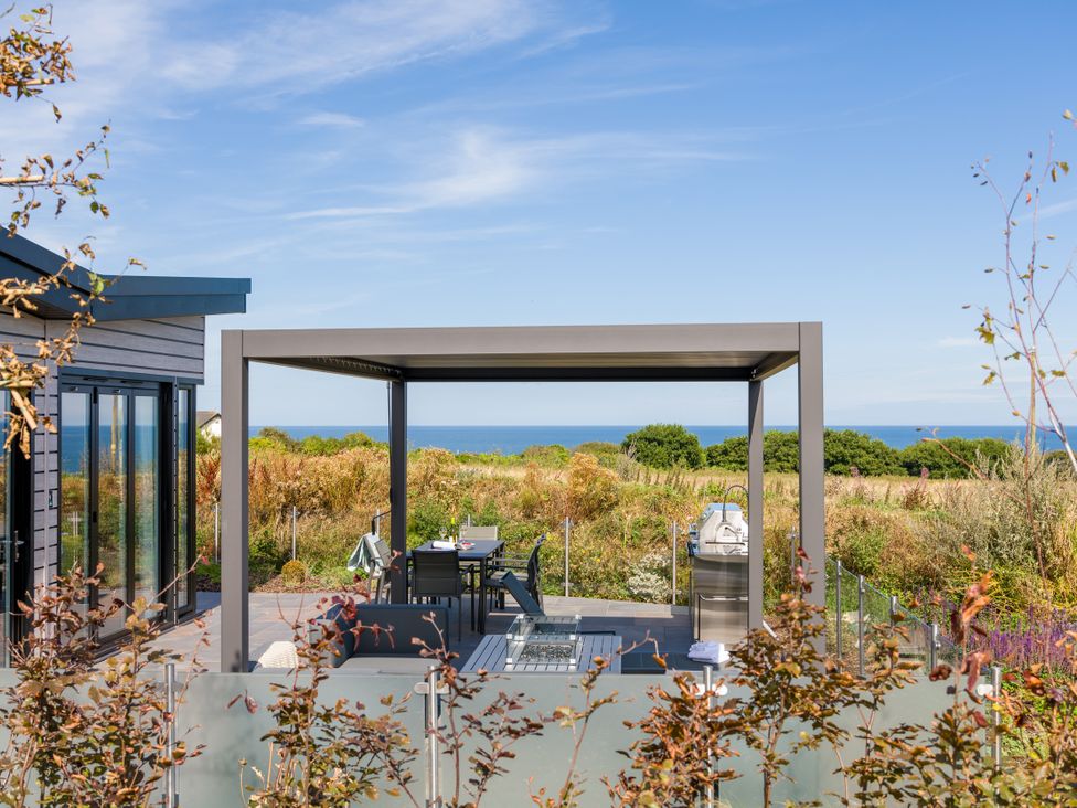 An outdoor area with a table and chairs under a pergola at Costal Lodge at Seaham Hall Seaham