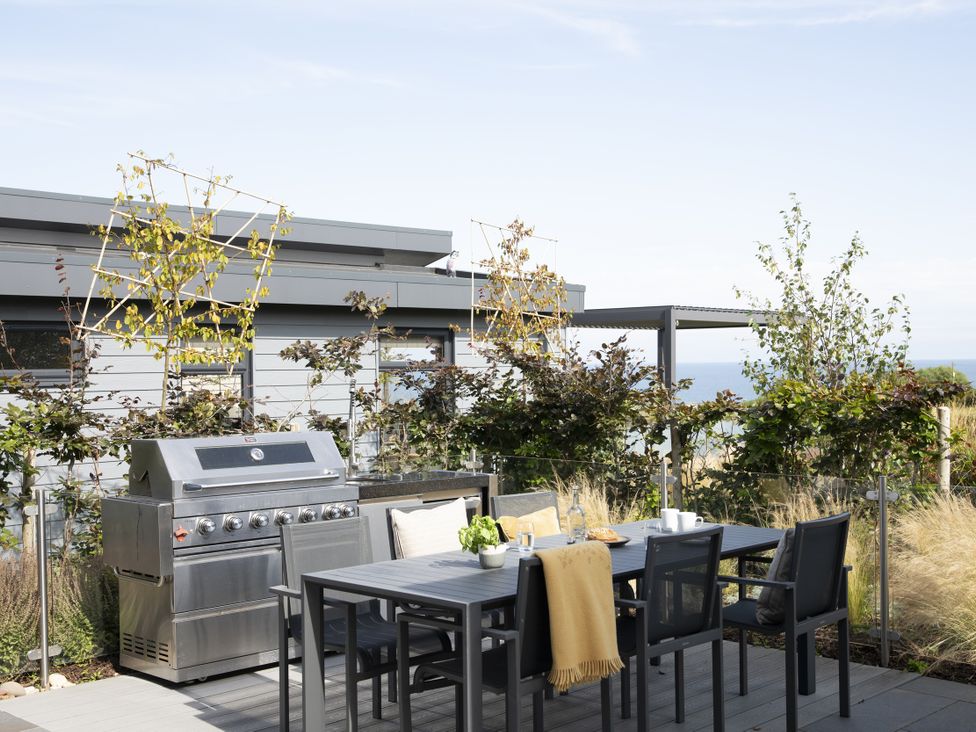 An outdoor dining area with a grill and table at Costal Lodge at Seaham Hall in Seaham