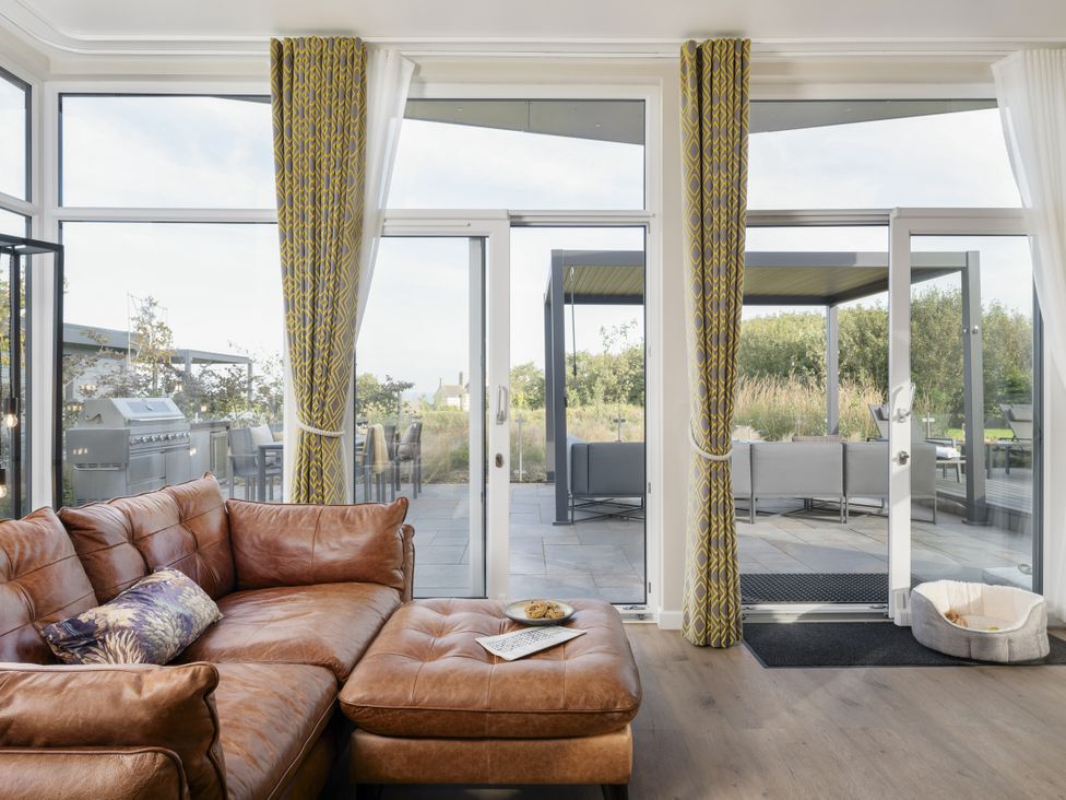 A living room with a brown couch and glass doors at Costal Lodge at Seaham Hall, Seaham