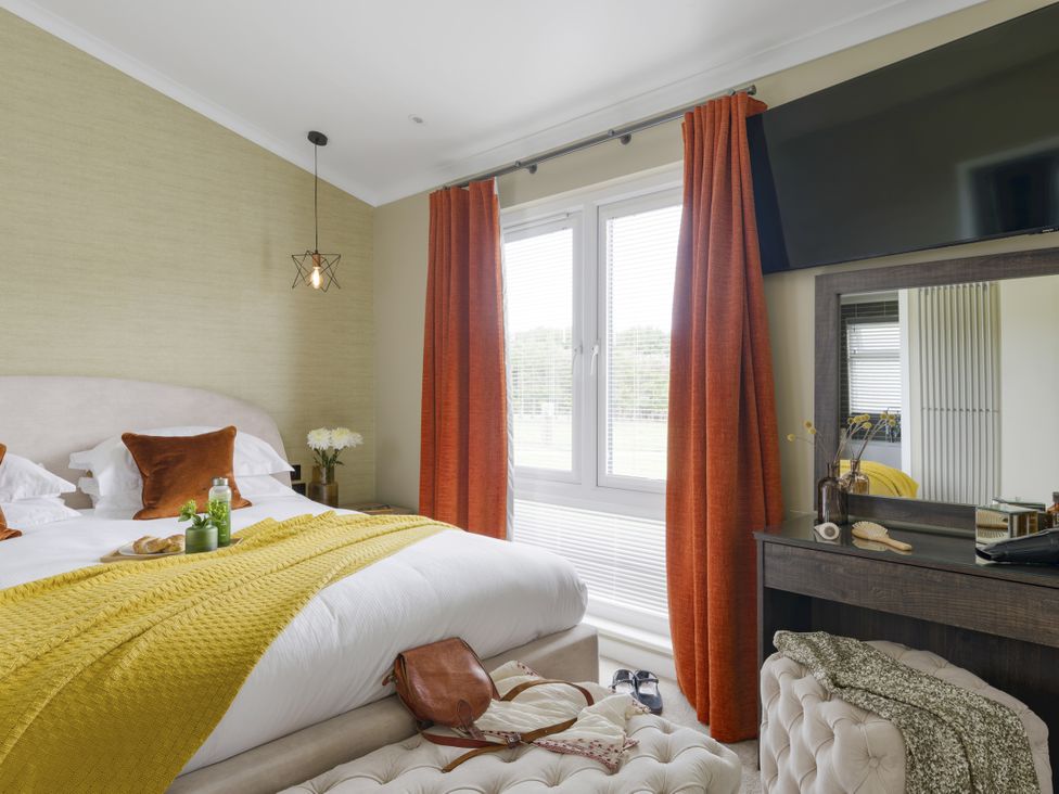 A bedroom with a bed and dresser at Costal Lodge at Seaham Hall in Seaham