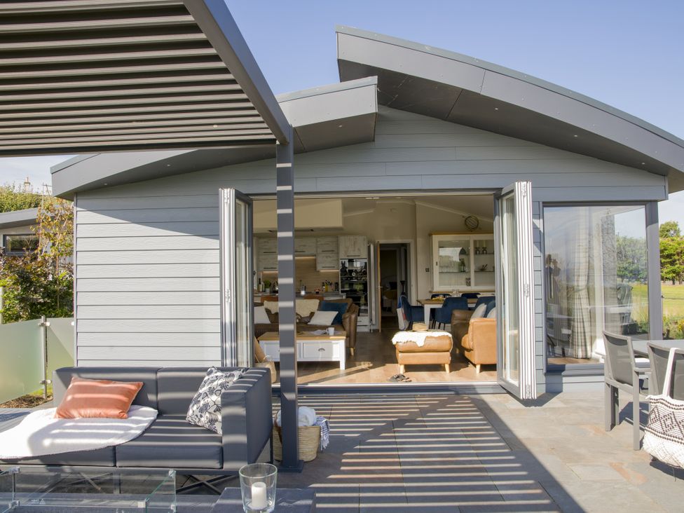 A patio with a couch and table leading into a living space at Costal Lodge at Seaham Hall Seaham