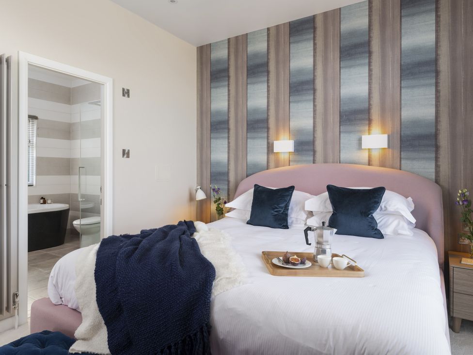 A bedroom with a bed, tray, and adjacent bathroom at Costal Lodge at Seaham Hall, Seaham