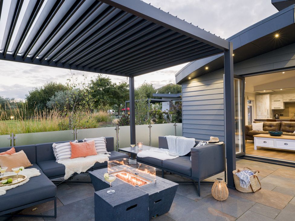 An outdoor seating area with a fire pit and sofa at Costal Lodge at Seaham Hall Seaham