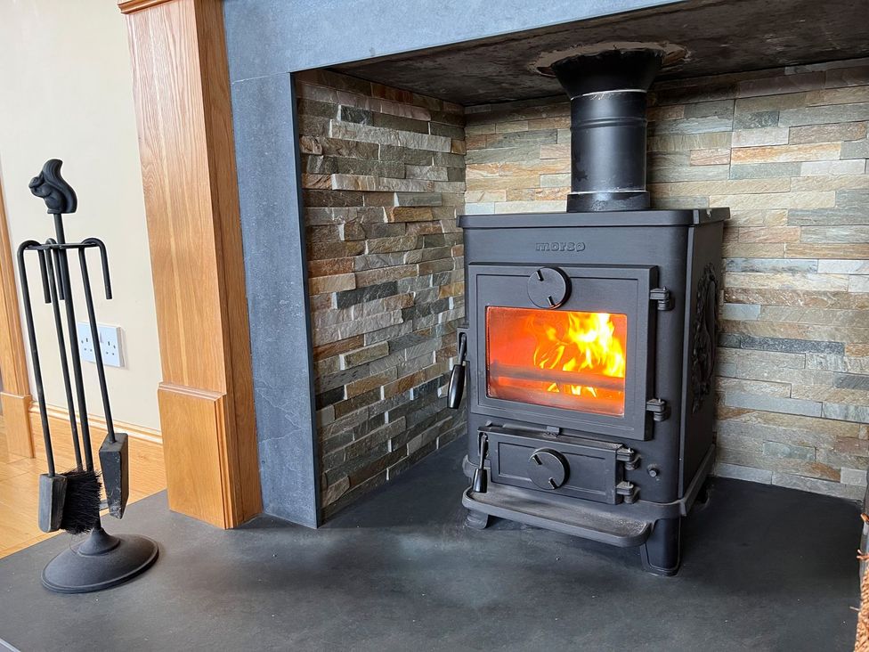 A wood stove with fire in a living room at Airigh nam Fiadh in Creagorry