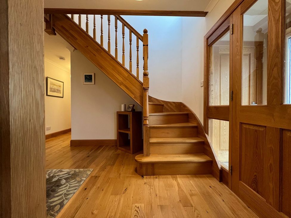 A hallway with a staircase and wooden cabinet at Airigh nam Fiadh in Creagorry