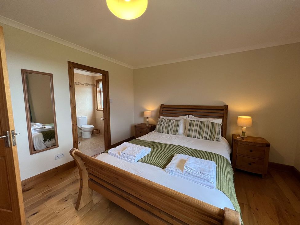 A bedroom with a bed and adjoining bathroom at Airigh nam Fiadh, Creagorry