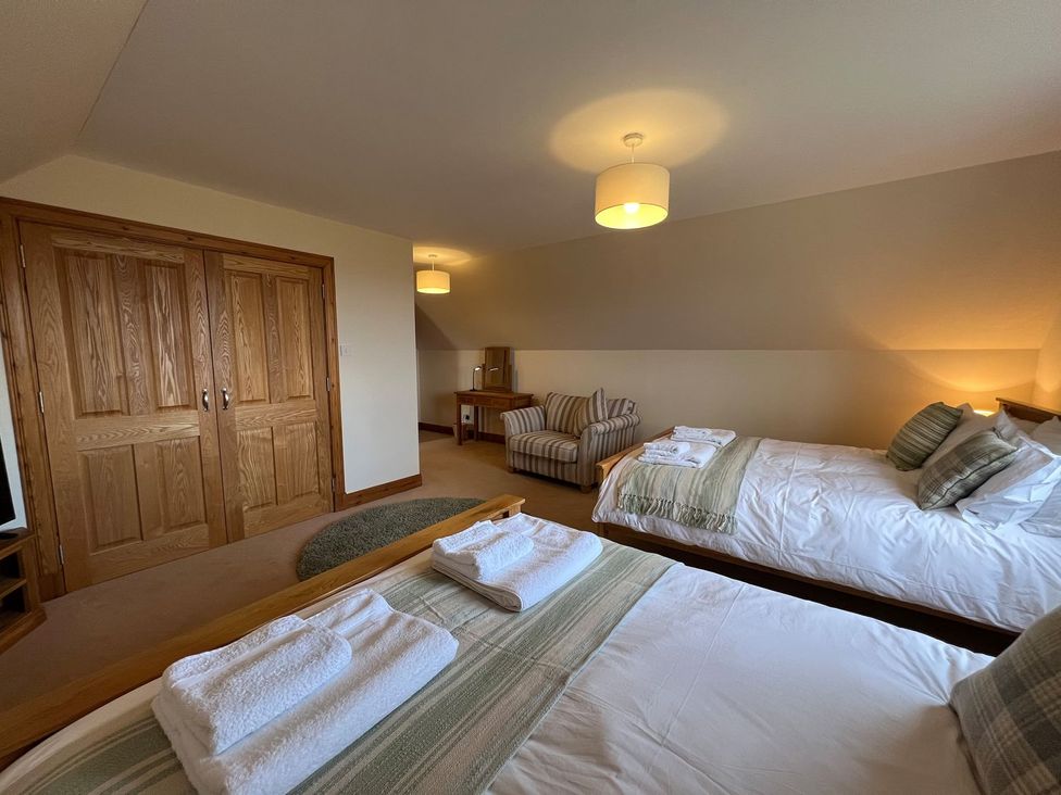 A bedroom with two beds and an armchair at Airigh nam Fiadh in Creagorry