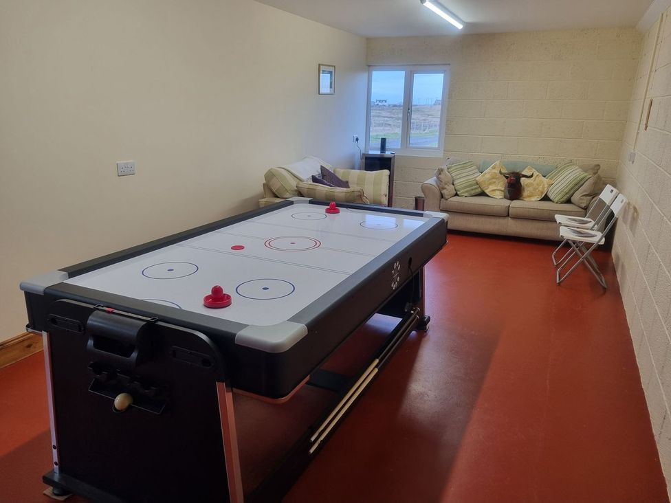 A snug with an air hockey table and a sofa at Airigh nam Fiadh Creagorry