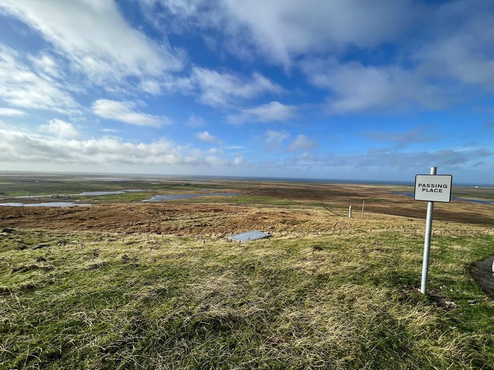 A passing place sign in a landscape with fields and water at Airigh nam Fiadh in Creagorry