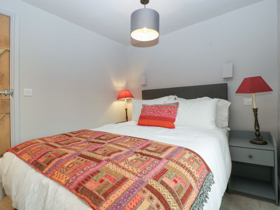 A bedroom with a bed, bedside lamps, and a patterned blanket at 3 bed property
