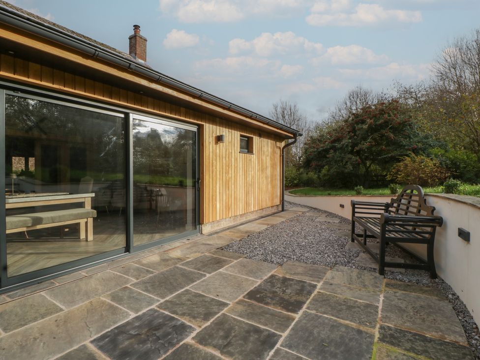 An outdoor patio area with a bench and stone flooring at 3 bed property
