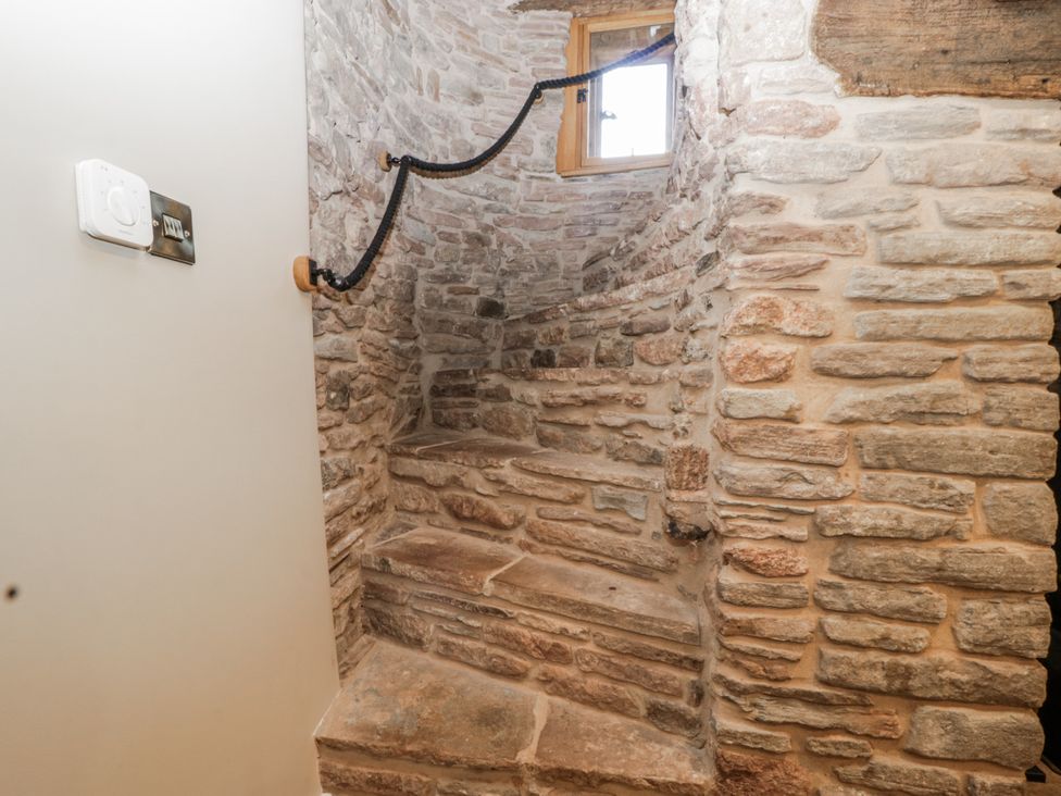 A staircase with stone walls and a window at 1 bed property Usk