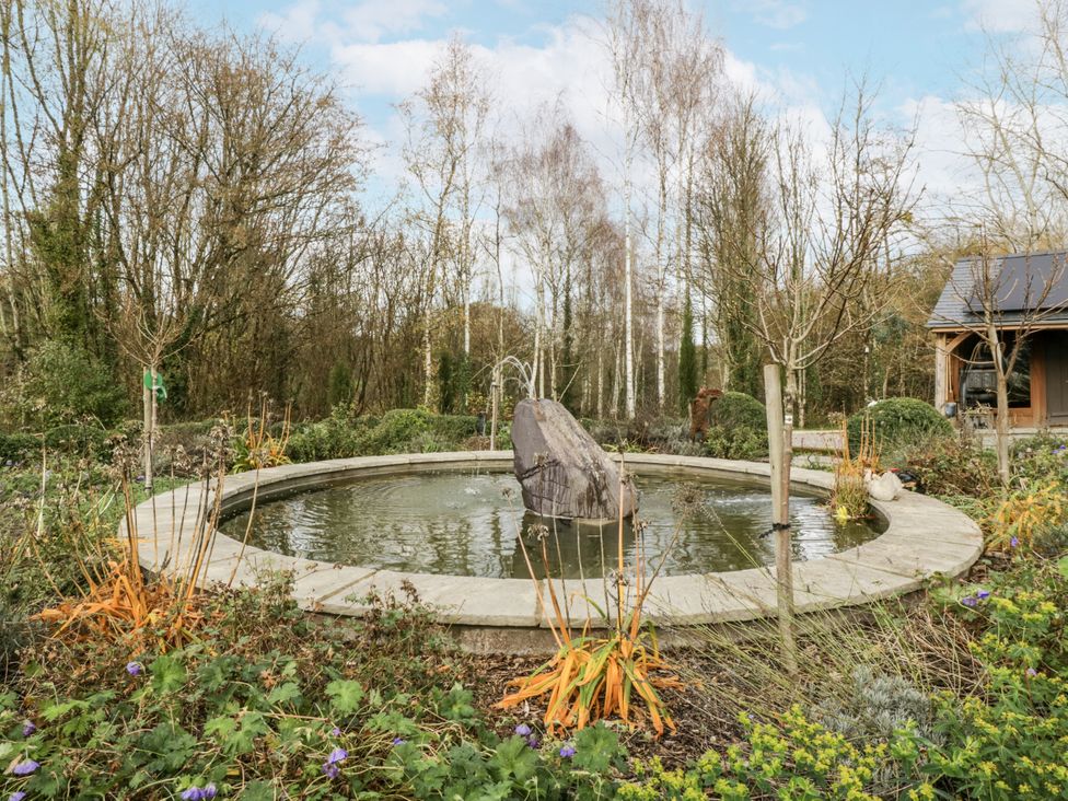 A pond with a stone feature surrounded by plants at 1 bed property Usk
