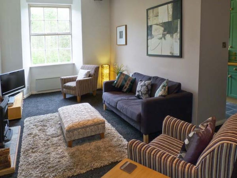 A living room with a television, sofa, and armchairs at 14 Riverside Walk in Skipton