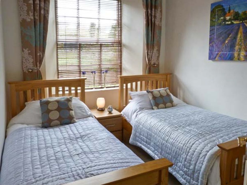 A bedroom with two single beds and a window at 14 Riverside Walk Skipton