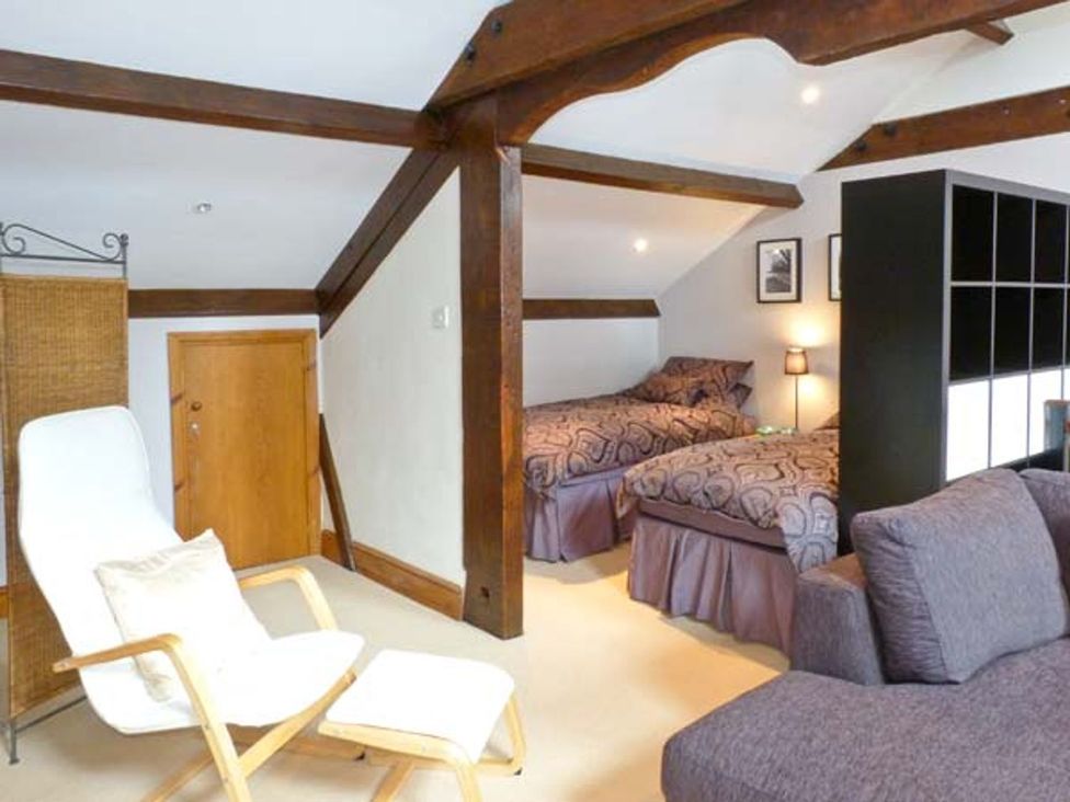 A bedroom with two beds, an armchair, and a door at 14 Riverside Walk Skipton